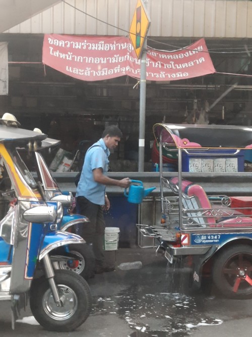 A driver washes his tuktuk at the end of the day