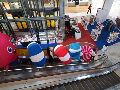 A flock of entertainers travel in an escalator at an upmarket shopping mall