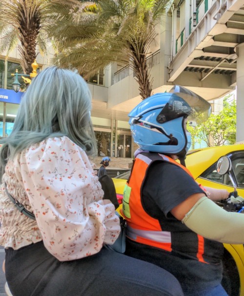 Driver and passenger in a scooter navigating Bangkok's infamous traffic.