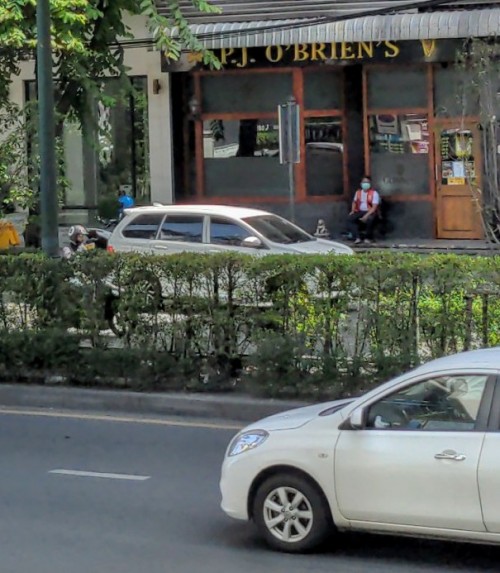 A solitary moto driver sitting in front of a long-closed Irish bar in Sukhumvit.