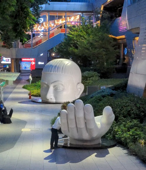 A security guard checks the hand of an art installation in CentralWorld, Bangkok.