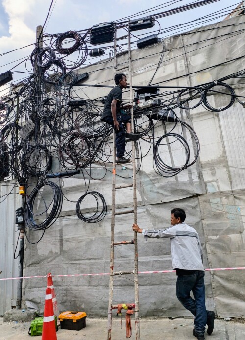 In Bangkok most telecomm cables are an overhead jungle toed in loops to utility poles. Safety is minimal and bamboo ladders "de rigueur".